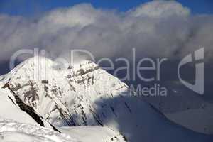 snowy sunlit mountains and blue sky with clouds