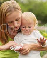 portrait of a crying little boy who is being held by her mother