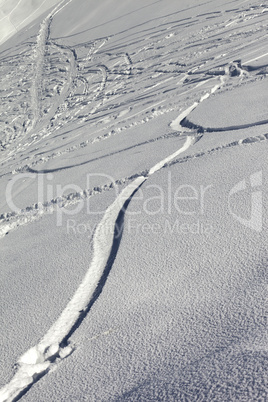 trace of ski and snowboards in newly-fallen snow