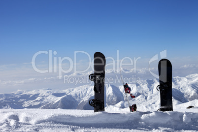 three snowboards in snow near off-piste slope in sun day