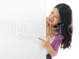 Asian woman pointing to blank billboard.