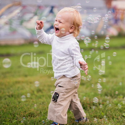 little  boy  runs and  catches soap bubbles