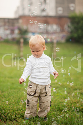 little  boy catches soap bubbles