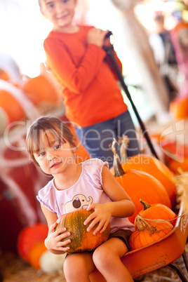 Cute Girl Riding Wagon with Her Pumpkin and Sister