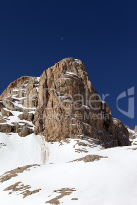Snowy rock and cloudless sky with moon