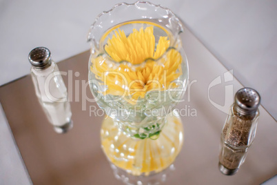 yellow flowers in glass bowl with salt and pepper