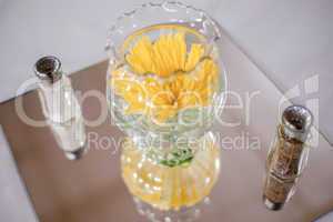 yellow flowers in glass bowl with salt and pepper