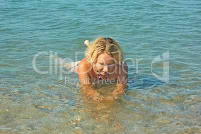 Teenage girl lies in shallow seawater