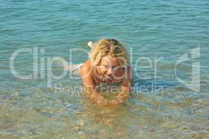 Teenage girl lies in shallow seawater