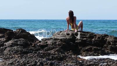 Young attractive woman sitting on the rocks