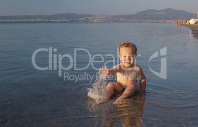 cute little boy splashing in the sea