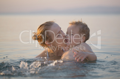 mother playing in the sea with her little son