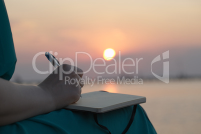 woman writing in her diary at sunset