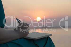 woman writing in her diary at sunset