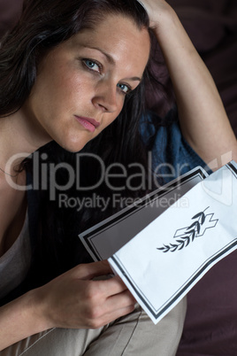 Portrait of young widow holding obituary