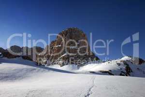 Snowy plateau and footpath against rock and blue sky in nice day