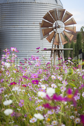 Antique Farm Windmill and Silo in a Flower Field .