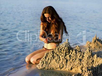 girl builds a sand castle on the beach