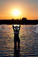 girl standing in the lake at sunset