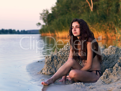 young girl sitting on the shore of lake