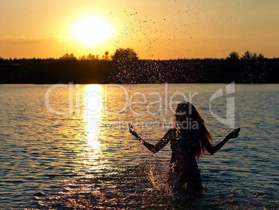 girl standing in the lake at sunset