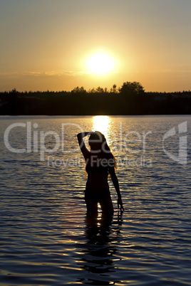 girl standing in the lake at sunset