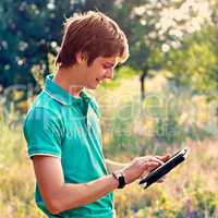 young guy with a tablet outdoors