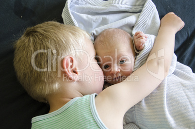 baby beeing cuddled by his big brother