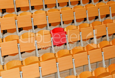 Empty classroom with wood chairs and one red chair