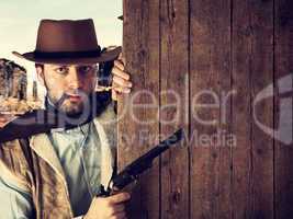 bad gunman indicates with the gun a wooden plank
