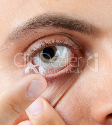 view of a man's green eye while inserting a corrective