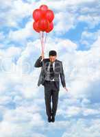 Businessman flying with red balloons