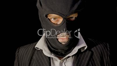 Masked criminal showing up laughing close up