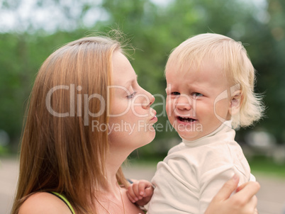 crying little boy who is being held by her mother