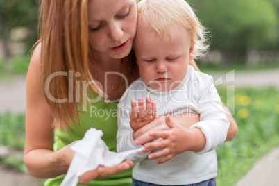 portrait of a crying little boy who is being held by her mother