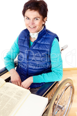 woman with book sitting in a wheelchair at the table