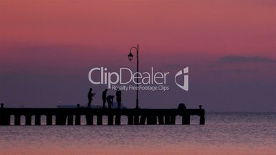 People on a pier at sunset