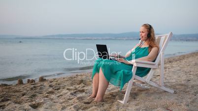 Woman relaxing at the beach with her laptop talking skype