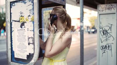 woman chatting on a public telephone