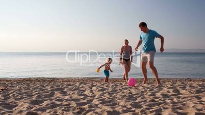 Young family playing football on the beach