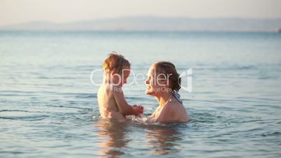 mother playing with her young son in the sea