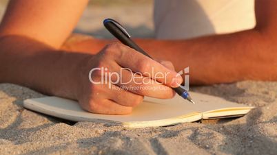 Man writing in his diary at the beach