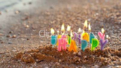 Birthday candles burning on a seashore