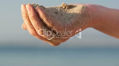 Woman drizzling sea sand through her fingers