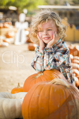 little boy smiles while leaning on pumpkin at pumpkin patch