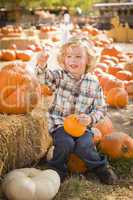 little boy sitting and holding his pumpkin at pumpkin patch.