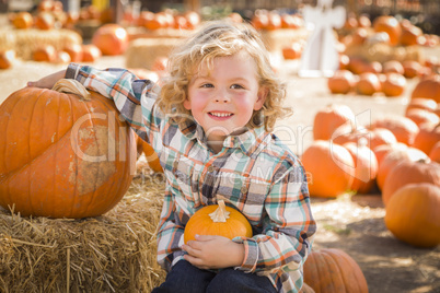 little boy sitting and holding his pumpkin at pumpkin patch.