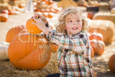 little boy sitting and holding his pumpkin at pumpkin patch.