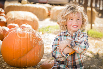 little boy sitting and holding his pumpkin at pumpkin patch.