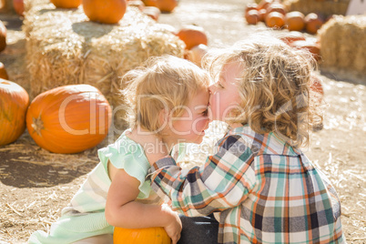 sweet little boy kisses his baby sister at pumpkin patch.